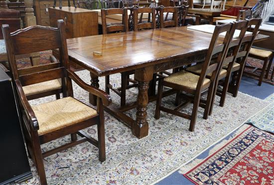A 17th century style oak draw leaf dining table with a set of ten rush seat chairs including two carvers extends 277 x 107cm